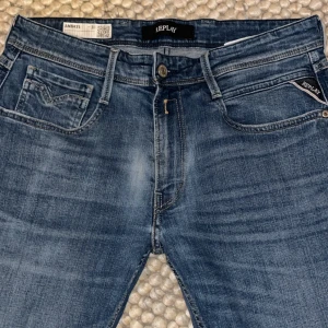Replay Anbass  - Snygga Replay Anbass jeans i klassisk blå tvätt med lätt slitning. Modellen har fem fickor. Jeansen är tillverkade i stretchigt denim för extra komfort och har Replay-logga på fickan. Perfekt för dig som gillar stilrena och moderna jeans. Pris kan diskuteras 