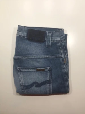 Nudie jeans 👖  - Säljer ett par blåa jeans från Nudie jeans! Storlek: W30 L32 (bild 4) Modell: Thin Finn (Bild 5/sista) Nypris: 1600kr, mitt pris: 349kr. Enda defekten är att Nudie tagen är borttvättad (Bild 2) Skriv vid funderingar och diskuterar gärna priset!