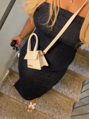 Marinblå axelbandslös långklänning Zara - Säljer en stilren marinblå axelbandslös långklänning från Zara. Klänningen har en figurnära passform och är gjord i jeansmaterial som ger en cool och modern vibe. Perfekt för dig som gillar minimalistisk och trendig stil.