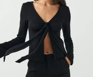 Svart långärmad topp med knyt - Säljer en svart långärmad topp från Pieces med v-ringning och snygg knytning framtill. 