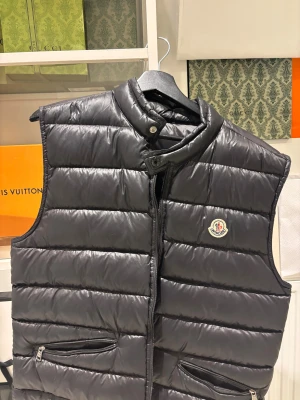 Svart dunväst från Moncler - Tjena, säljer en Moncler Gui bäst i storlek M, jackan har en skada vid dragkedjan men får fortfarande att stänga därefter priset