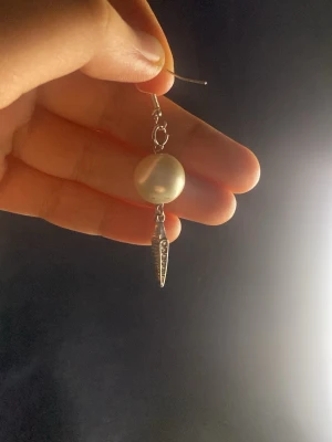Maria Nils dotter liknande Vit pärlörhänge med silverdetalj - Maria Nilsdotter liknade  snygga örhängen med en stor vit pärla och en spetsig silverfärgad hängande detalj med små glittrande stenar. Perfekt för dig som gillar att sticka ut med accessoarer. Kroken är i metall och designen är modern och cool. SÄLJS SOM PAR❤️