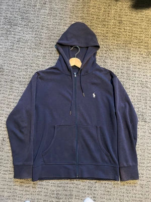 Mörkblå sipp hoodie från polo Ralph Lauren -  En mörkblå sipp hoodie från polo Ralph Lauren med vit märke i storlek S. perfekt som dig som vill ha en fin hoodie