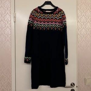 Mörkblå stickad tröja med mönster - Mörkblå stickad tröja fmed färgglatt geometriskt mönster. Tröjan har lång ärm och rund hals, perfekt för dig som gillar färg och mönster.