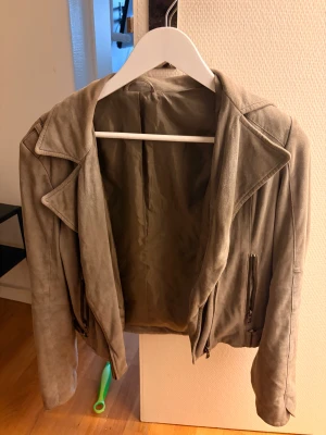 Jacka i mockaimitation  - Snygg jacka i mocka, lite missfärgningar baktill och runt kragen men går säkert att få bort! Köpt på second hand tror jag. Skulle säga att färgen är mer åt greige hållet. 