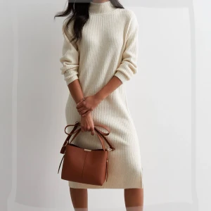 Beige stickad klänning New Look - Mysig beige stickad klänning från New Look i ribbat material. Klänningen har polokrage, långa ärmar och slitsar i sidorna. Perfekt för dig som gillar en enkel och stilren look.