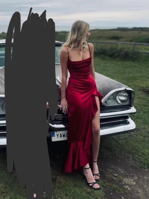 Vinröd bal klänning från Lucy in the sky - Vinröd bal klänning i satin liknande material med smala axelband, draperad urringning och hög slits med volangkant. Baksidan har snygg snörning som ger en extra detalj. Perfekt för bal eller fest och ger en riktigt elegant vibe. Användes en gång för min studentbal och är i ny skick. Köpets nypris inklusive tull för 1500☺️😇