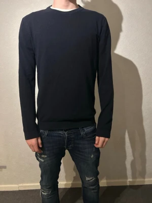 Mörkblå tröja från Lindbergh White - Snygg mörkblå tröja från Lindbergh White i storlek S. Tröjan har rund halsringning med ribbad kant och långa ärmar. Modellen är 183