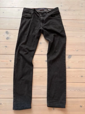 Svarta jeans från Alberto straight fit - Svarta jeans från Alberto med klassisk femficksdesign och raka ben. Snygga orangea sömmar på insidan och diskret svart patch med perforerat mönster bak. Jeansen har normal passform och är tillverkade i bomull med lite stretch för extra komfort. Skick 9/10, storlek 31/34 men sitter som 31/32! 