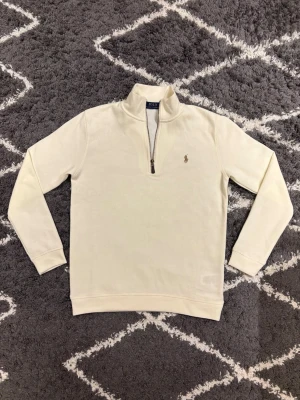 Polo Ralph Lauren half zip - Snygg vit långärmad tröja från Polo Ralph Lauren med klassisk ståkrage och half zip-dragkedja framtill. Tröjan har det ikoniska Polo-logot broderat på bröstet och är gjord i mjuk bomull. Storlek S. Jag är 180cm och den passar mig perfekt.