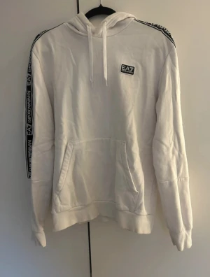 Emporio Armani hoodie  - En fin vit Hoodie från emporio Armani! Tröjan är helt skadefri, dvs mycket bra skick! Storleken är M men passar även dig som har L. Hör av dig vid frågor samt funderingar!
