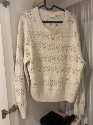 Beige stickad tröja från Vila - Köpt för 400kr. Säljer en beige stickad tröja från Vila med snyggt hålmönster och rund hals. Tröjan har långärmade ärmar och ribbade muddar vid hals, ärmslut och nederkant. Perfekt för dig som gillar en chill och stilren look.
