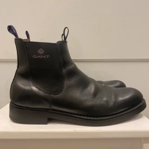 GANT chelsea boots  - Svarta chelsea boots från Gant i läder med elastiska paneler på sidorna och dragflikar både fram och bak.  Är i mycket fint skick utan större defekter. Skafthöjd: 13cm 