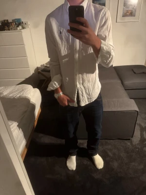 Vit linneskjorta Polo Ralph Lauren - Vit långärmad skjorta från Polo Ralph Lauren i slim fit. Tillverkad i linne med klassisk krage, knappar framtill och broderad blå logga på bröstet. Perfekt för en clean och stilren look.