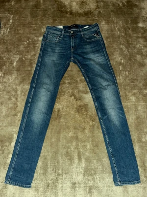Replay Anbass blå jeans - Säljer ett par Replay Anbass jeans i klassisk blå tvätt med snygga slitningar. Använt och sparsamt skick!  Perfekta för dig som gillar en clean och tidlös look.
