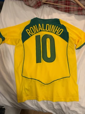Nike Brasil Ronaldinho fotbollströja M - Retro Brasilien-tröja med Ronaldinho-tryck, starka färger och fint skick. Ikonisk modell som är riktigt eftertraktad. Svår att få tag på i det här skicket. Köps ofta direkt – lägg i varukorgen och köp innan den försvinner. ✅Brställ nu = Kommer innan jul ✅Ställ frågor = Snabba svar