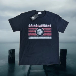 Saint Laurent  T-Shirt  - Säljer den här ysl tishan, skit fet och väldigt eftertraktad. Riktigt nice nu inför sommarn, passar till allt. Priset är förhandlingsbart, skicka prisförslag. Taggen ingår ej