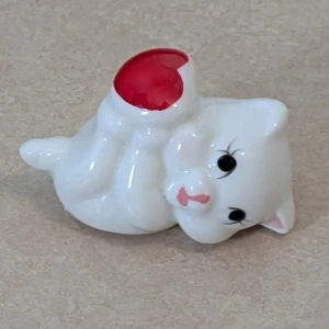 Jätte söt katt som håller ett hjärta  - En söt figur av en vit katt som ligger på rygg och håller ett rött hjärta..Perfekt som dekoration eller present till någon som älskar gulliga djur och inredning.