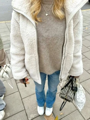 Vit teddyjacka - Säljer en fluffig vit teddyjacka med hög krage och dragkedja framtill. Jackan har en oversized passform och är tillverkad i mjukt fleece-material som håller dig varm. Säljer för att den inte kommer till användning, den har inga defekter men har blivit använd ett antal gånger 