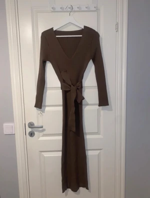 Klänning med band / bälte i midjan - Högst bud 196kr.  Lite tjockare stickat tyg i Mockabrun färg.