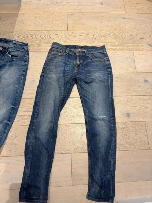 Nudie Jeans blå jeans 30/34 slim fit  - Säljer ett par klassiska blå jeans från Nudie Jeans i modellen 30/34. De har en snygg tvätt med slitningar och kontrastsömmar. SLIM FIT 