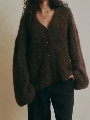 Alpacka tröja  - Mysig brun kofta med fluffig känsla och v-ringad hals. Koftan har stora, långa ärmar och knäpps med svarta knappar framtill. Perfekt för dig som gillar oversized och chill stil. Materialet känns mjukt och värmande, passar till höst och vinter.