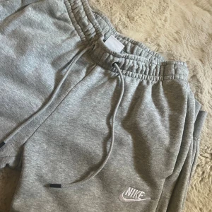 Grå mjukisbyxor från Nike XS - Grå mjukisbyxor från Nike i storlek XS. Byxorna har resår och snörning i midjan, muddar vid bensluten och klassisk Nike-logga broderad på benet. 