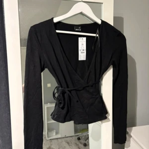 Topp med knytning - En superfin långärmad svart tröja med knytning runt midjan som inte längre säljs, storlek XS💗 Den är helt oanvänd och har prislappen kvar!! Jag köpte den för 280kr men priset kan diskuteras vid snabb affär💞