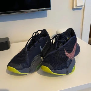 Nike sneakers i marinblå och neon - Lossnat en liten bit från sulan som man ser på bilden och så finns det några färgsläpp, men inget som påverkar.