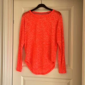 Orange långärmad sporttröja H&M - Säljer en neonorange långärmad sporttröja från H&M Sport i storlek S. Tröjan har ett melerat mönster och är tillverkad i ett lätt och mjukt material som passar perfekt för träning. Rund halsringning och något längre baktill för en snygg passform.