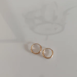 Guldiga små hoops örhängen - Säljer ett par stilrena små hoops i guldton. De är enkla, runda och passar perfekt för dig som gillar minimalistiska smycken. Perfekta att bära varje dag för en clean look.