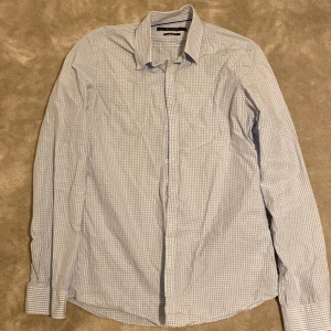 Blårutig skjorta från Tiger of Sweden - Blårutig skjorta från Tiger of Sweden i slim fit-modell. Skjortan är tillverkad i 100% bomull. Stilren, fin ljusblå färg. Är öppen för ett lägre pris vid snabb affär. Om ni har några frågor skriv gärna!