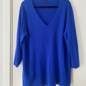 Kornblå stickad v-ringad tröja - Snygg kornblå stickad tröja från H&M med djup v-ringning och trekvartsärm. Modellen är loose fit och har slitsar i sidorna för extra chill vibe. Perfekt att slänga på över ett linne eller t-shirt. Mjuk och skön kvalitet. Mått Över bröstet: ca 64 cm Längd från axeln och ner: ca 74 cm  100% merinoull   Kommer från ett djur och rökfritt hem.