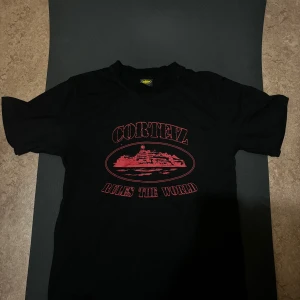 Corteiz t shirt - Svart t-shirt från Cortez i storlek small med röd tryckt grafik och texten 'Cortez Rules The World' på bröstet. Klassisk passform och rund hals. Tillverkad i mjuk bomull, perfekt för en avslappnad streetstyle.
