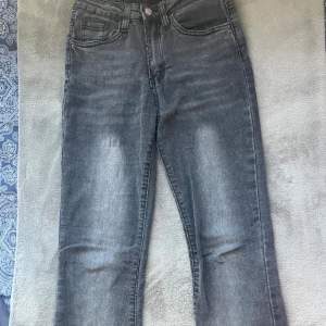 Grå bootcut jeans med tvättad look - Snygga grå jeans med bootcut passform och tvättad effekt. Jeansen har klassisk femficksdesign och raka ben som blir vidare nedtill. Perfekta för dig som gillar en avslappnad men trendig stil.