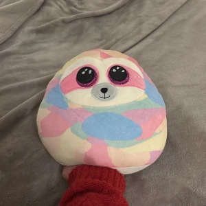 Ty Pastell Sloth Kudde - Supermjuk och färgglad Ty kudde i form av en söt sengångare med stora glittriga ögon. Pastellfärger i rosa, blått, gult och lila. Perfekt skick, inga synliga defekter eller slitage. Mysig som prydnad eller kramkudde i sängen eller soffan.
