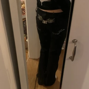 Svarta byxor med broderi och nitar - Svarta byxor med snygga silvriga broderier och nitar på bakfickorna samt ett BB-emblem. Byxorna har raka ben och normal passform. Perfekta för dig som gillar detaljer och vill sticka ut lite extra.