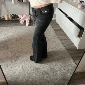 Svarta bootcut jeans med låg midja - Säljer ett par svarta bootcut jeans  och låg midja. Jeansen har silverfärgade knappar framtill. Passar dig som gillar en cool och avslappnad stil.