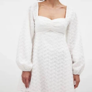 Vit blommig kortklänning med puffärm - Superfin vit kortklänning med broderade blommor och puffiga långärmar. Klänningen har fyrkantig urringning och lätt markerad midja. Tunt, transparent tyg med fodrad insida ger en romantisk vibe. Perfekt för sommarens alla tillfällen och studenten!