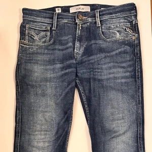 Blå Replay Anbass jeans - Sköna blå Replay Anbass jeans med klassisk femficksdesign och ljusare tvätt på låren. Jeansen har gylf med knapp, läderpatch bak och detaljerade sömmar. 