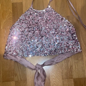 ONESIZE festtopp med paljetter  - Säljer en glittrig topp med paljetter. Toppen knyts i nacke och rygg, så storleken kan justeras. Passar XS, S, M, L  beroende på hur man knyter det. Perfekt till fest, nyår eller en utekväll. I princip ny, bara använd en gång. 
