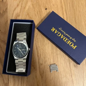 Silverfärgad klocka från Poedagar - Stilren klocka från Poedagar med silverfärgat metallarmband och mörk blå urtavla. Klockan har dag- och datumvisning samt klassisk kvartsrörelse. Levereras i originalask och extra länk medföljer. Perfekt för dig som gillar snygga accessoarer.