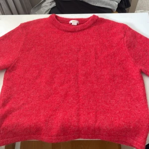 Röd stickad tröja från Gina Tricot - Mysig röd stickad tröja från Gina Tricot med rund halsringning och ribbade muddar. Perfekt för kyliga dagar och enkel att matcha med jeans eller kjol. Klassisk modell som funkar till allt.