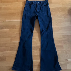 Bootcut jeans från Bershka - Snygga svarta bootcut jeans från Bershka med klassisk femficksdesign och dragkedja. Byxorna har hög midja och är tillverkade i en mjuk bomullsblandning med lite stretch för extra komfort. Perfekt för dig som gillar retrovibbar och markerade ben.