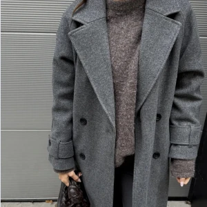 Warm trenchcoat  - Snygg grå kappa från Nelly med dubbelknäppning, bälte i midjan och stora slag. Lång modell med knappar vid ärmslut och sidfickor. 
