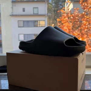 Adidas Yeezy Slide mörk grå strl 44/ 1/2 - Säljer ett par mörk gråa yeezy slides pga att jag inte använder dem. De är i bra skick, använd ett fåtal par gånger.  De är i storlek 44 1/2 men har krympts till 43.   Skriv vid flera frågor. Pris kan diskuteras.