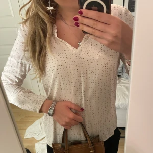 Prickig vit blus från EDC, stl M - Säljer en ljusrosa/cremvit blus från EDC med svarta prickar, v-ringad hals och knappdetalj vid kragen. Blusen har långa ärmar och är gjord i ett lätt, mjukt material som känns skönt mot huden. Perfekt för dig som gillar stilrena mönster och en chill vibe.💕🥰