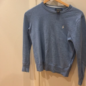 Blå sweatshirt från Polo Ralph Lauren - Snygg blå tröja från Polo Ralph Lauren i mjuk pima bomull. Klassisk rund halsringning, ribbade muddar och diskret broderad logga på bröstet. Perfekt för en clean och stilren look. Pris 319 kronor skick 9/10. Kontakta vid intresse