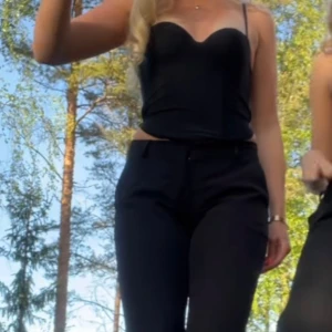 Svart korsettopp från H&M - Säljer en svart korsettopp från H&M med avtagbara axelband och formade kupor. Toppen har en figurnära passform och är gjord i ett mjukt polyestertyg med lite stretch. Perfekt till sommarens outfits och enkel att styla med olika accessoarer.