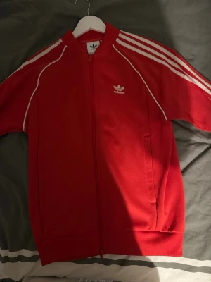 Röd Adidas zip hoodie - Säljer en röd Adidas hoodie i ett bra skick med lite slitage i ryggen. 
